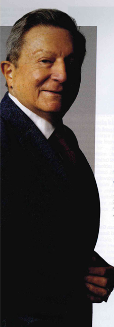 Portrait of a middle-aged man in a dark suit and tie, smiling slightly, facing left.